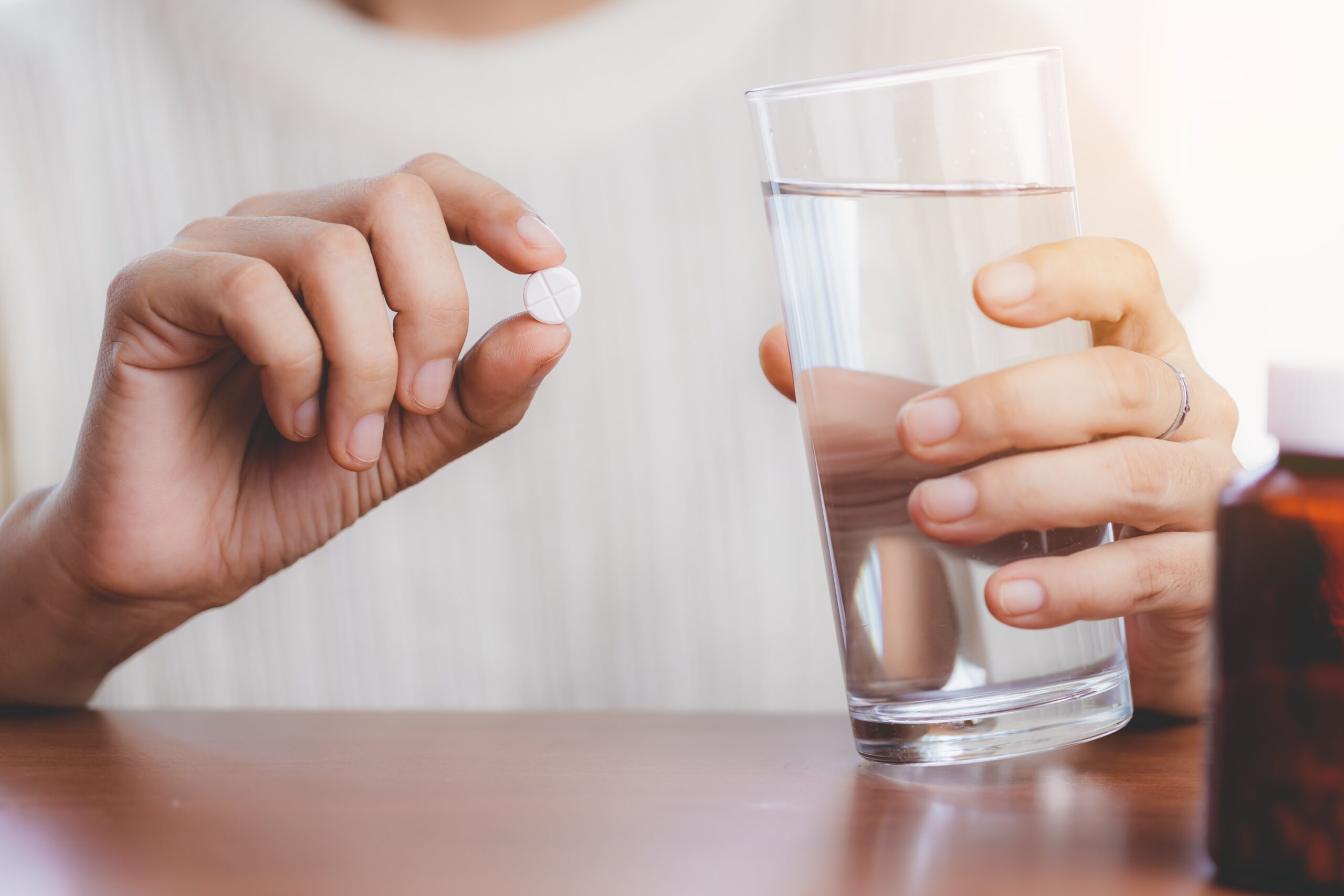 Woman's Hand Taking Medicine Pill And Drinking Water With The Br